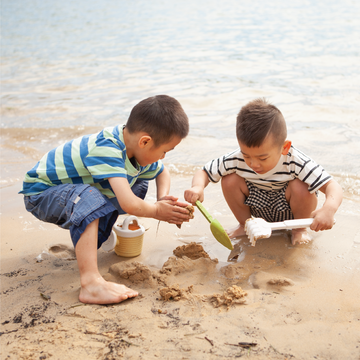 Preschool children aged 3 to 6 playing with a sandcastle set on the beach.