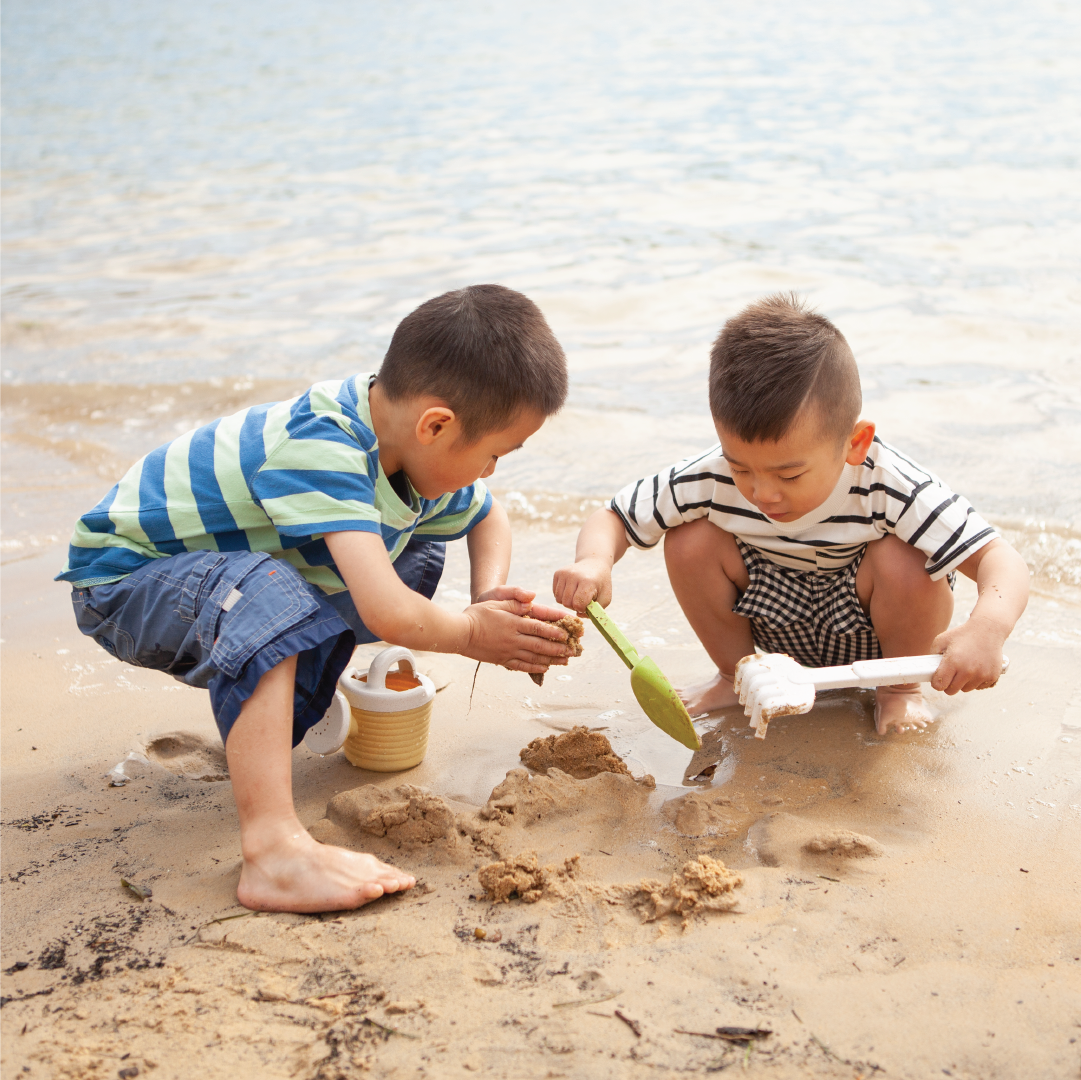 Preschool children aged 3 to 6 playing with a sandcastle set on the beach.